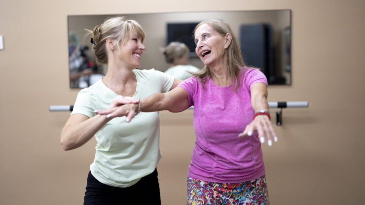 Two women joyfully engage in a dance class, embodying community spirit and vibrant energy.