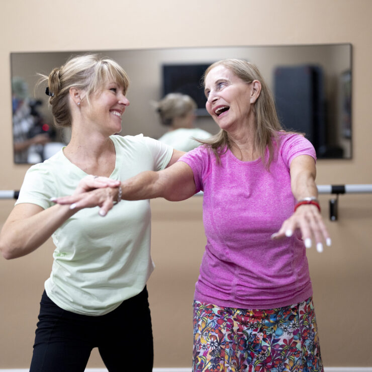 Two women joyfully engage in a dance class, embodying community spirit and vibrant energy.