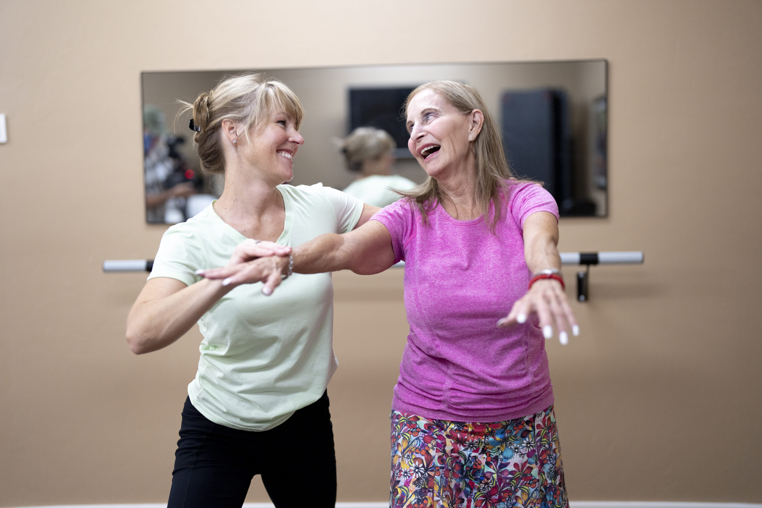 Two women joyfully engage in a dance class, embodying community spirit and vibrant energy.