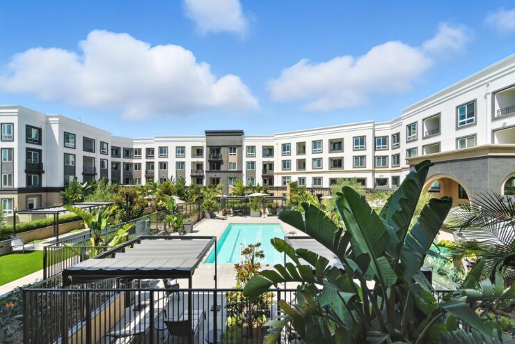 A vibrant community space with a serene pool area, surrounded by lush greenery and inviting architecture.