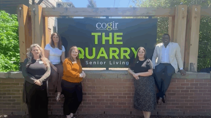 A welcoming team stands proudly by The Quarry sign, showcasing a vibrant community spirit and warmth.