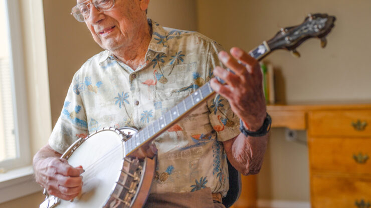 An engaging senior enjoys playing the banjo, creating a warm and inviting atmosphere for all.