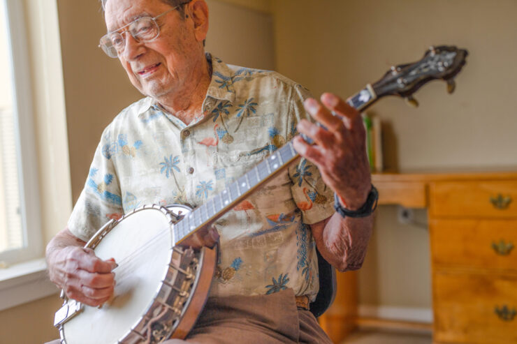 An engaging senior enjoys playing the banjo, creating a warm and inviting atmosphere for all.