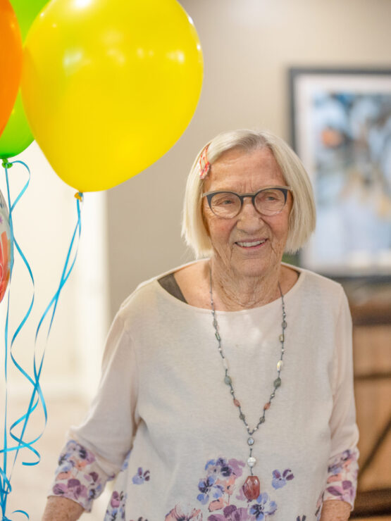 A resident joyfully celebrates a birthday, surrounded by colorful balloons, radiating warmth and community.