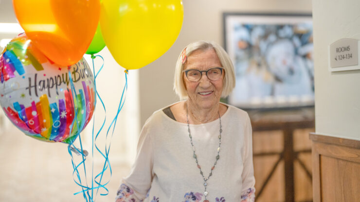 A resident joyfully celebrates a birthday, surrounded by colorful balloons, radiating warmth and community.