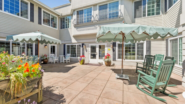 A vibrant courtyard filled with flowers, inviting seating, and sunny skies fosters community and relaxation.