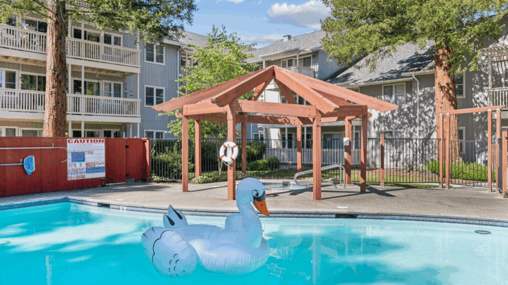 A serene pool area with a playful swan float, surrounded by lush greenery and welcoming homes.