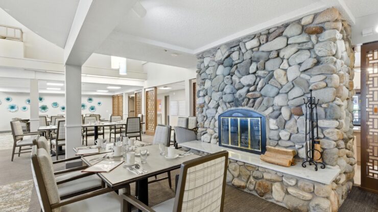 Bright and inviting dining area with stone fireplace, fostering warmth and community spirit.