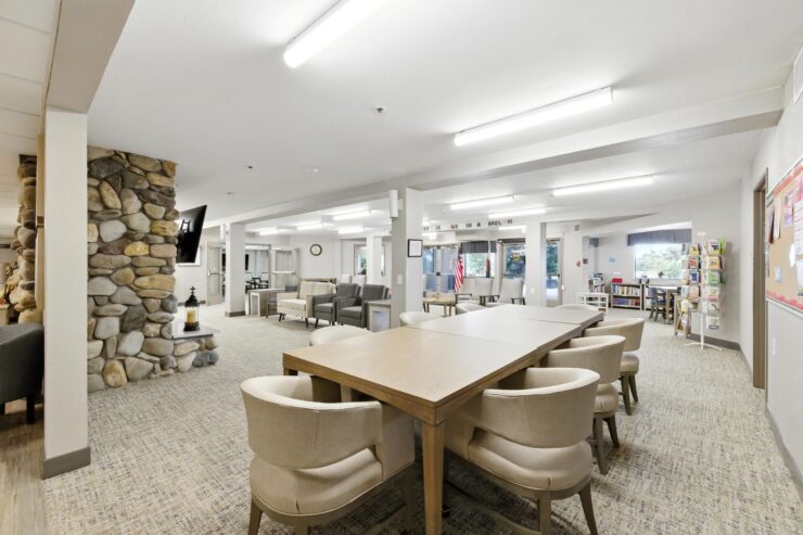 A welcoming common area filled with light, featuring comfortable seating and a communal table for gatherings.