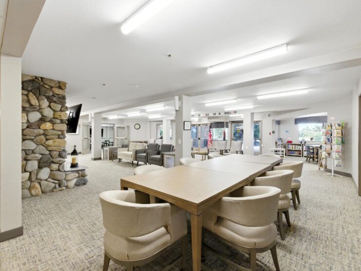 A welcoming common area filled with light, featuring comfortable seating and a communal table for gatherings.