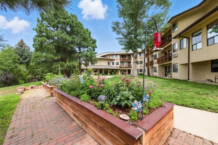 A vibrant garden welcomes residents to a tranquil community, surrounded by inviting buildings and greenery.
