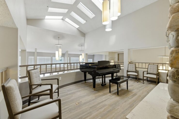 A bright, welcoming lounge features elegant seating and a piano, inviting community gatherings and joyful moments.