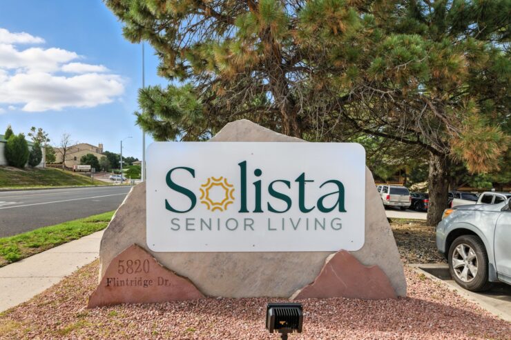 Welcoming sign for Solista Senior Living, surrounded by greenery, inviting a sense of community and warmth.