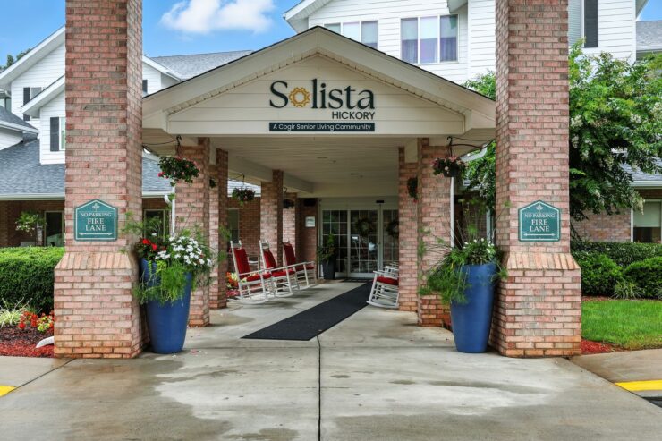 A welcoming entrance adorned with vibrant flowers and comfortable rocking chairs, inviting community and warmth.