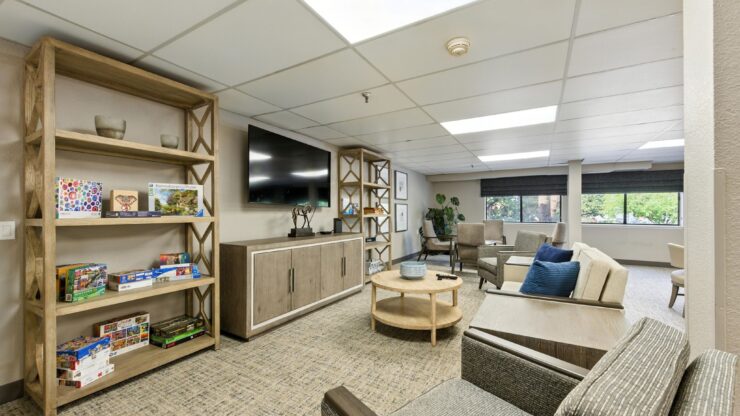 A welcoming communal space featuring comfortable seating, natural light, and vibrant shelves for connection.