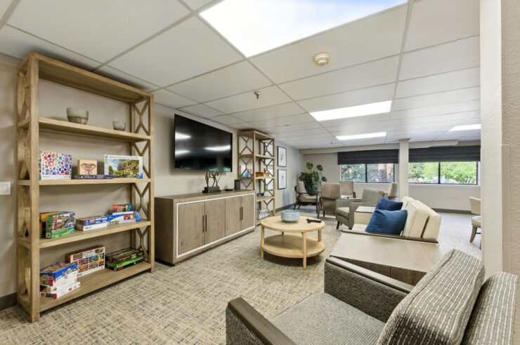 A welcoming communal space featuring comfortable seating, natural light, and vibrant shelves for connection.