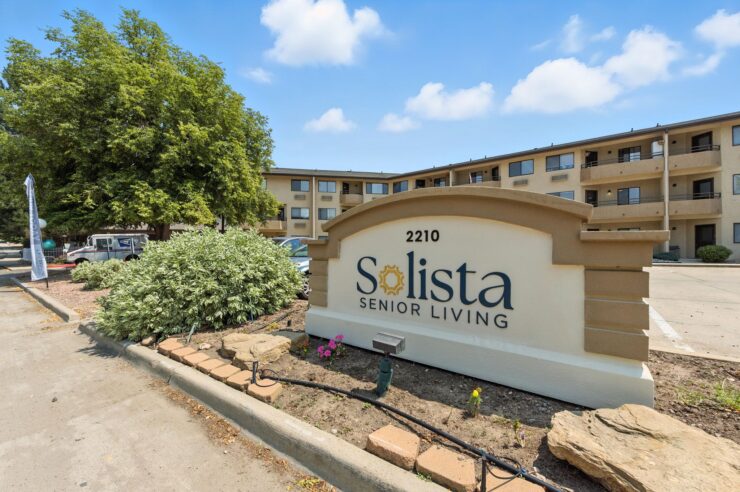 Welcoming sign at Solista Senior Living, surrounded by lush greenery, inviting a vibrant community atmosphere.