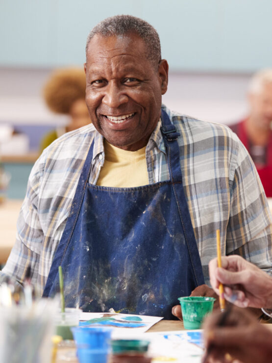 A vibrant art class filled with smiling residents, fostering creativity and connection among friends.