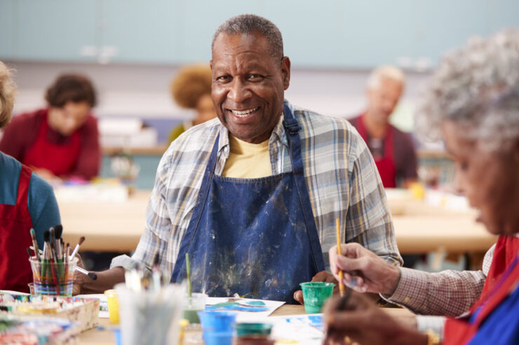 A vibrant art class filled with smiling residents, fostering creativity and connection among friends.