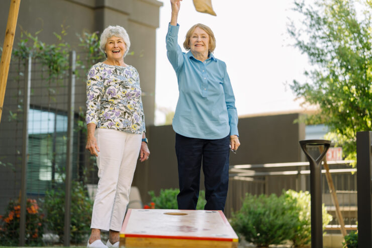 Two smiling women enjoy a lively game outdoors, fostering friendship and community spirit.