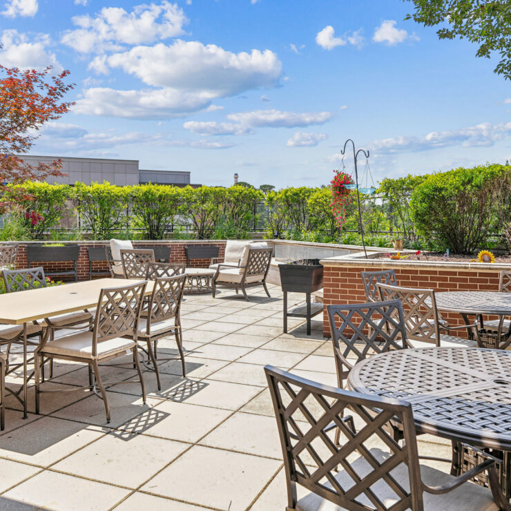 A welcoming outdoor space with comfortable seating, vibrant greenery, and bright skies invites community gatherings.