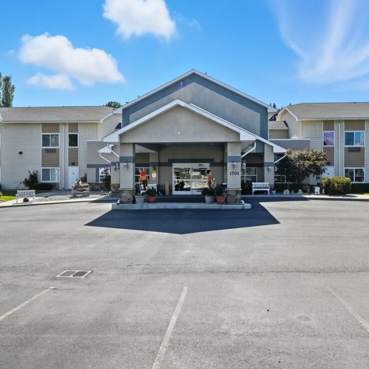 Bright, welcoming entrance of a retirement home with landscaped gardens and benches for relaxation.