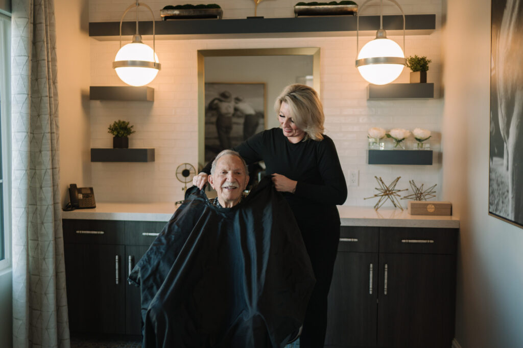 A warm, welcoming salon scene where a smiling resident enjoys a friendly haircut, fostering community spirit.