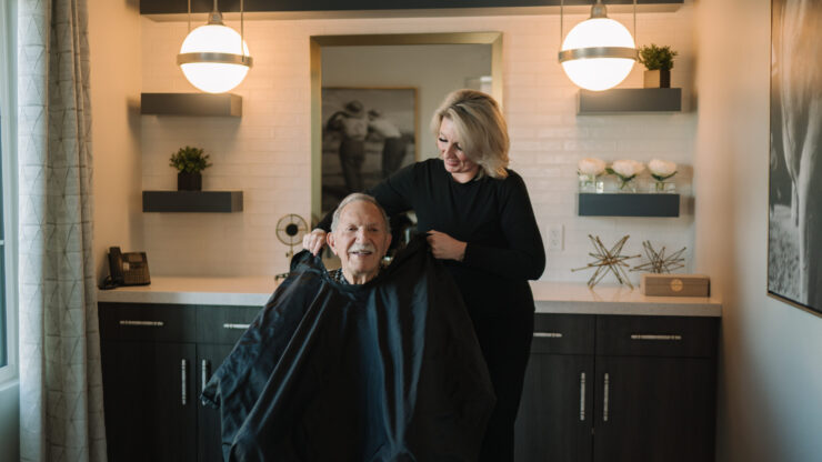 A warm, welcoming salon scene where a smiling resident enjoys a friendly haircut, fostering community spirit.