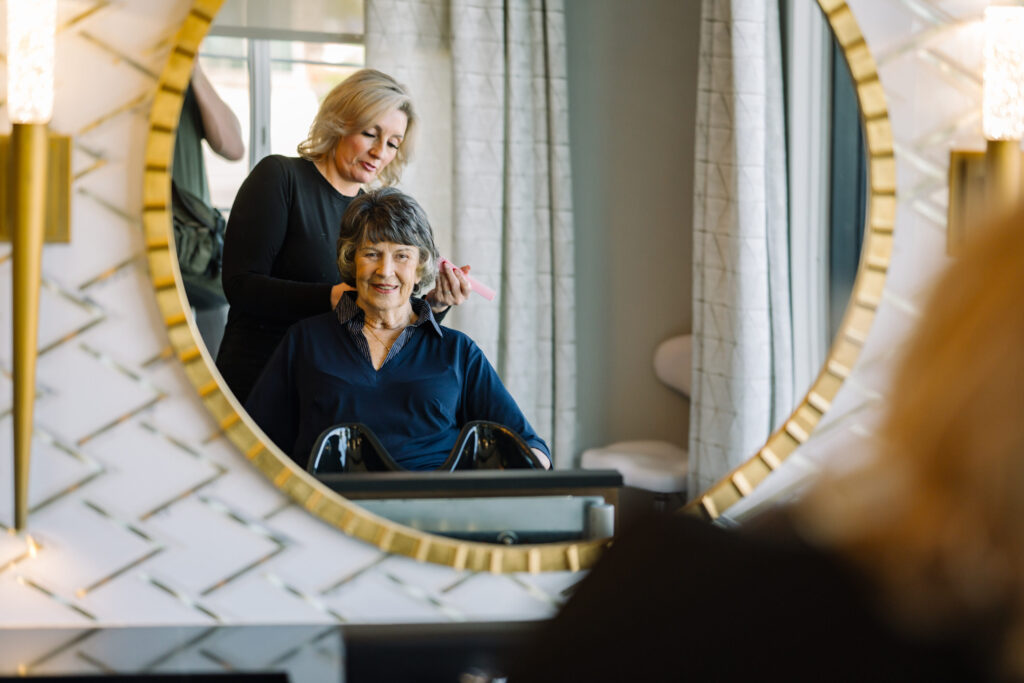 A warm, inviting salon scene where a stylist gently attends to a smiling resident, fostering community and care.