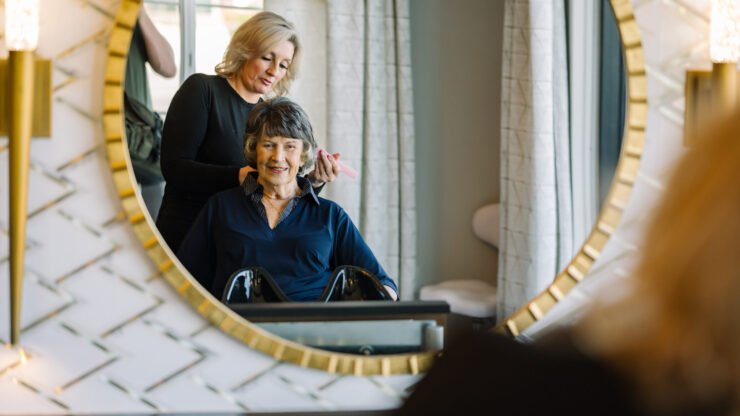 A warm, inviting salon scene where a stylist gently attends to a smiling resident, fostering community and care.