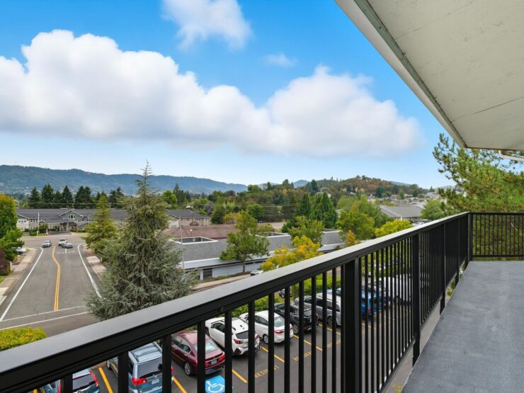 A serene balcony view showcasing lush greenery and gentle hills, inviting community and relaxation.