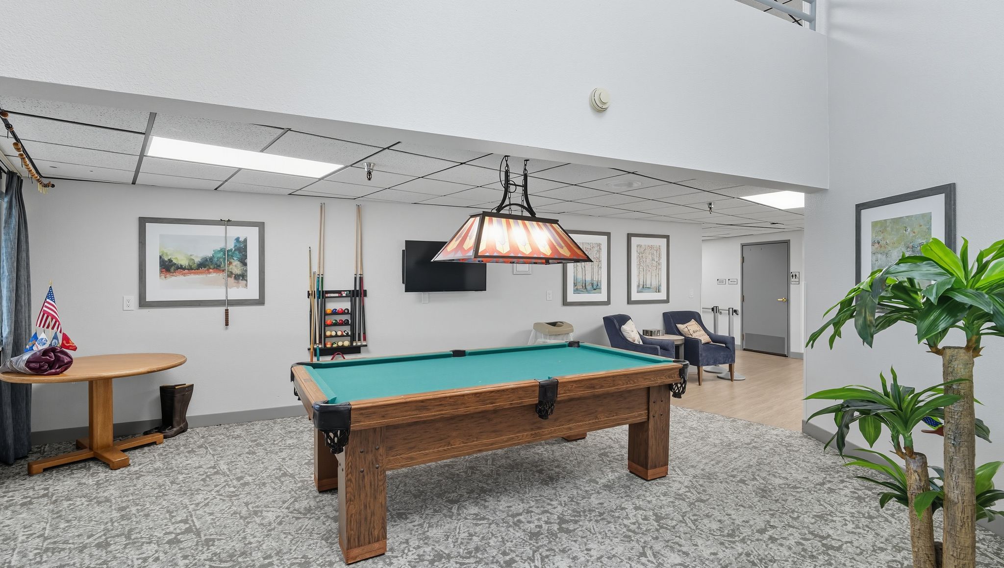 Spacious game room with pool table, comfortable seating, and warm lighting for socializing.