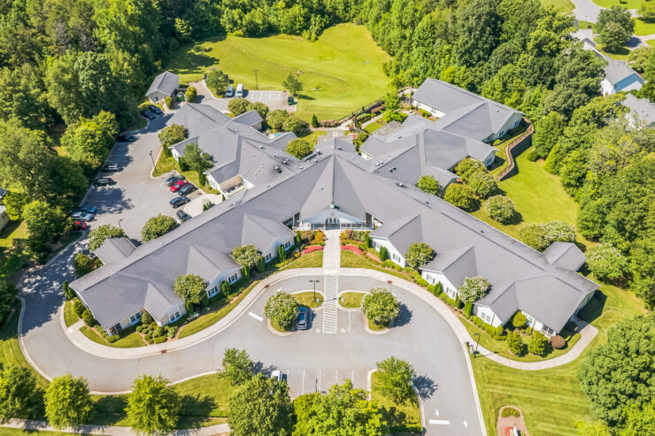 Retirement community surrounded by lush greenery with spacious parking and manicured lawns.