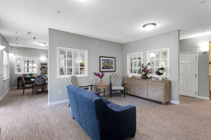 Bright community room with comfortable seating, fresh floral arrangements, and natural light.