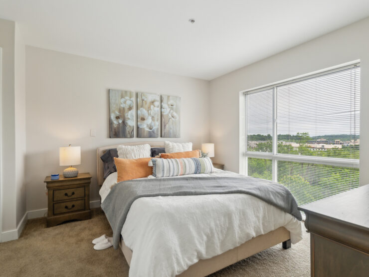 Bright, inviting bedroom with large window, soft bedding, and warm lighting for peaceful living.