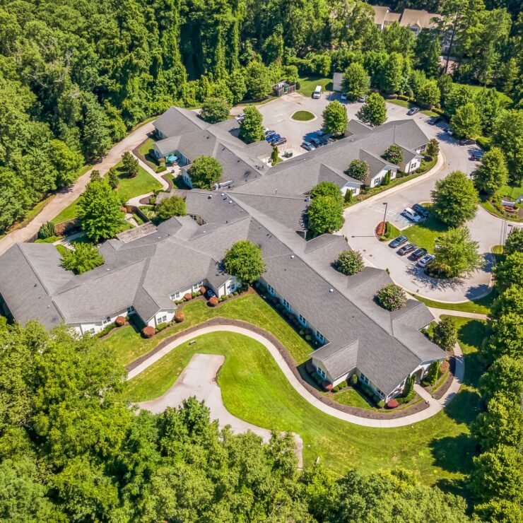 Well-maintained retirement community nestled among lush greenery with inviting pathways and parking.