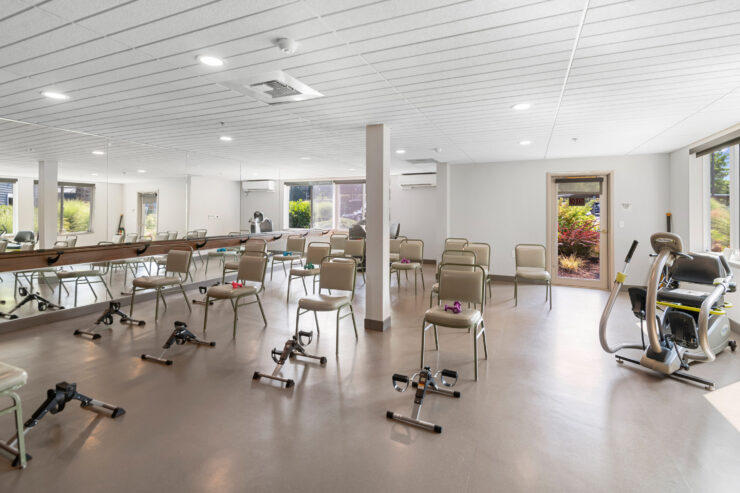 Bright and spacious exercise room with chairs, weights, and equipment promoting active community living.