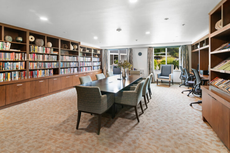 Well-lit library and meeting room with comfortable seating and abundant bookshelves.