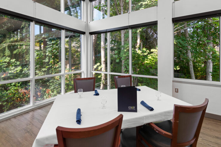 Dining area with natural light and forest views, set for an inviting meal together.