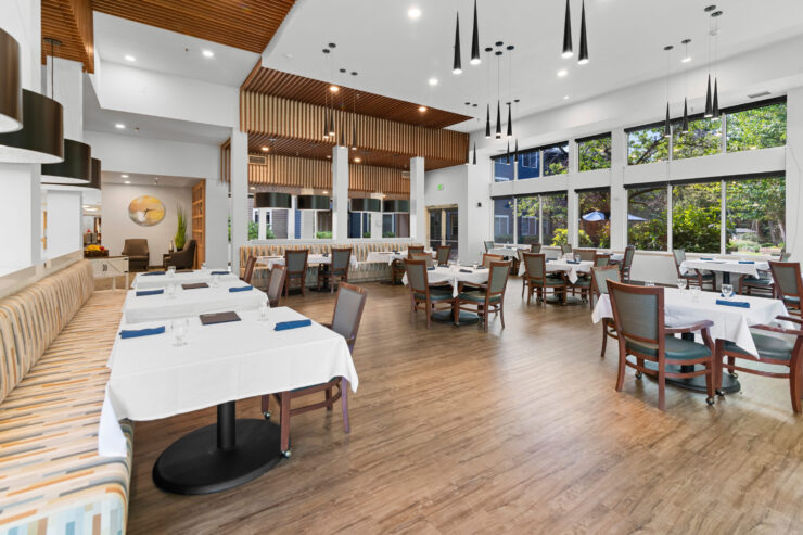 Bright and inviting dining area with ample seating and large windows overlooking greenery.