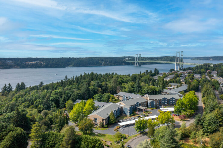 Retirement community nestled among trees with scenic waterfront and bridge views.