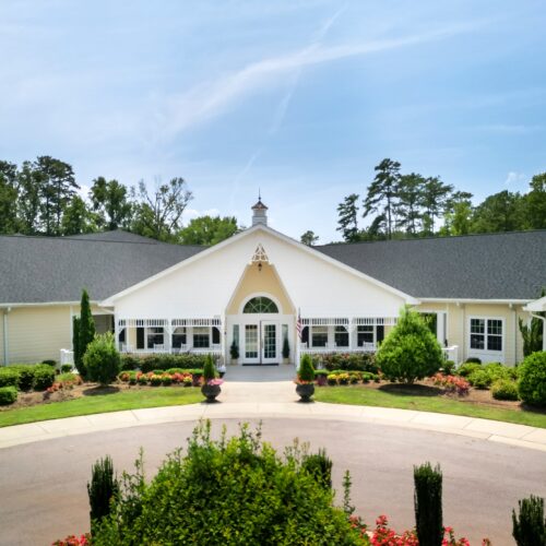 Well-maintained retirement home entrance surrounded by lush greenery and colorful flowers.
