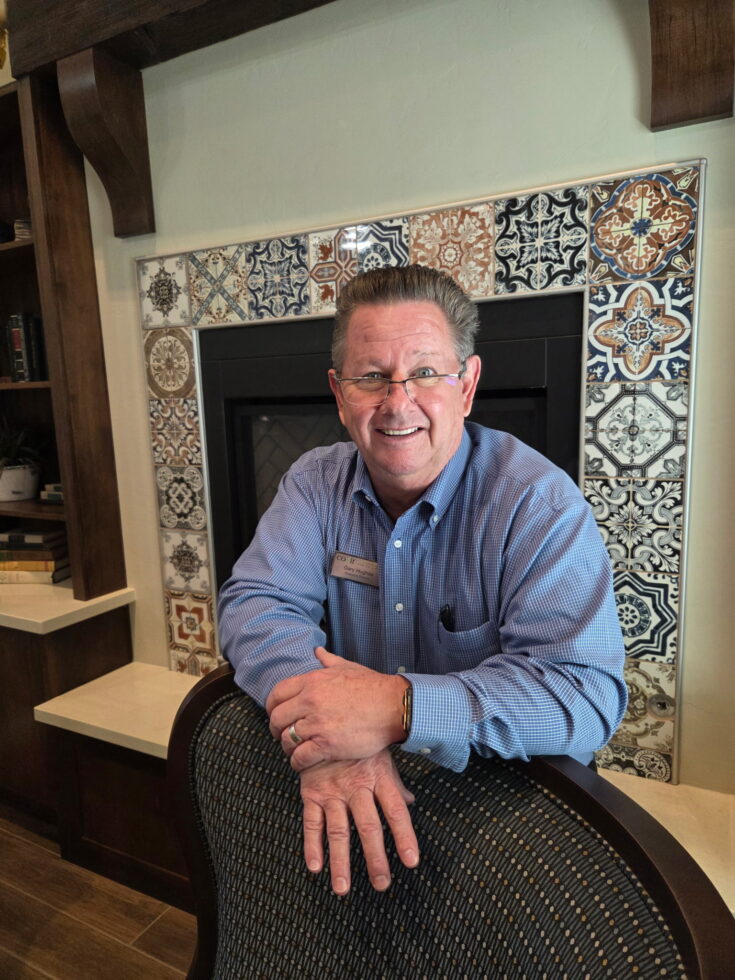 A welcoming staff member smiles warmly, embodying community spirit in a beautifully designed common area.