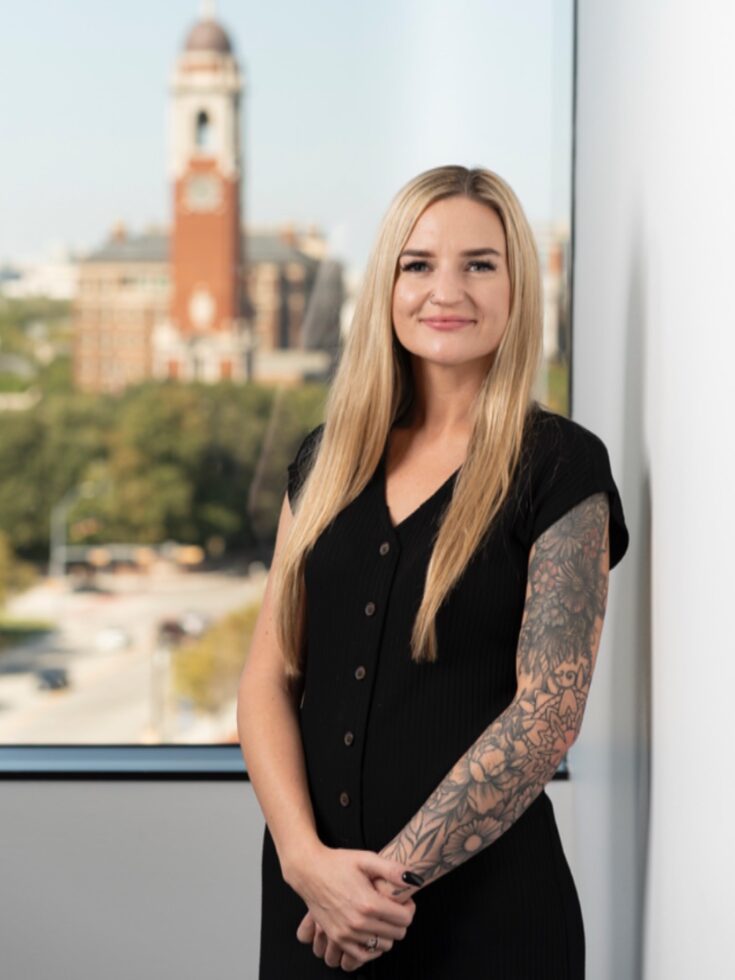 A welcoming professional stands by a bright window, showcasing a vibrant community outside.