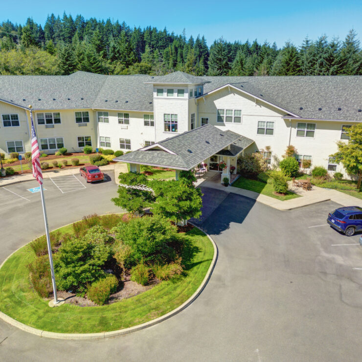 Bright and welcoming retirement community nestled among lush greenery with ample parking and outdoor seating.