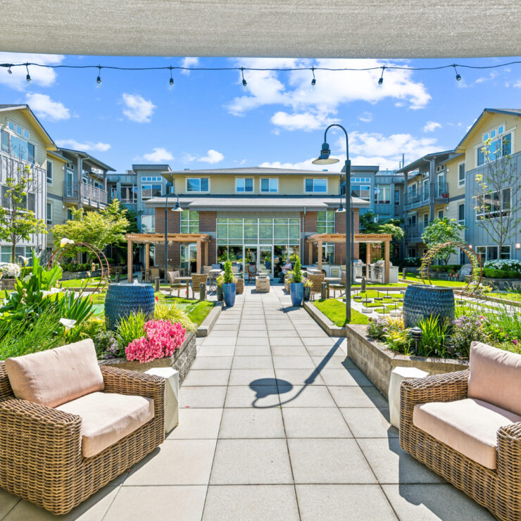 A vibrant courtyard invites relaxation, featuring comfortable seating and lush gardens, perfect for community gatherings.