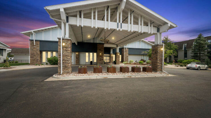 Welcoming entrance to a well-lit, inviting retirement community surrounded by landscaping.