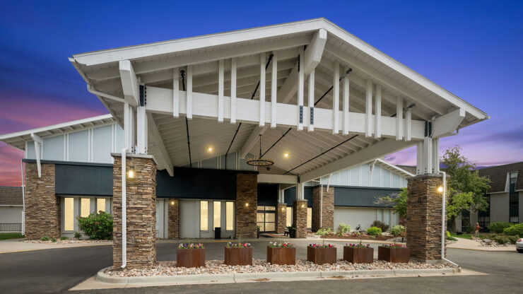 Welcoming entrance to a well-lit, inviting retirement community surrounded by landscaping.