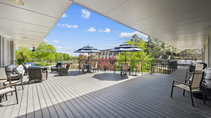 Spacious outdoor patio with comfortable seating and shaded tables overlooking lush greenery.