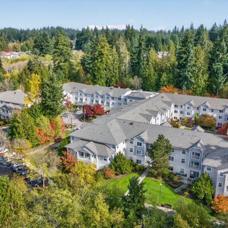 Retirement community surrounded by lush trees with vibrant fall colors and well-kept grounds.